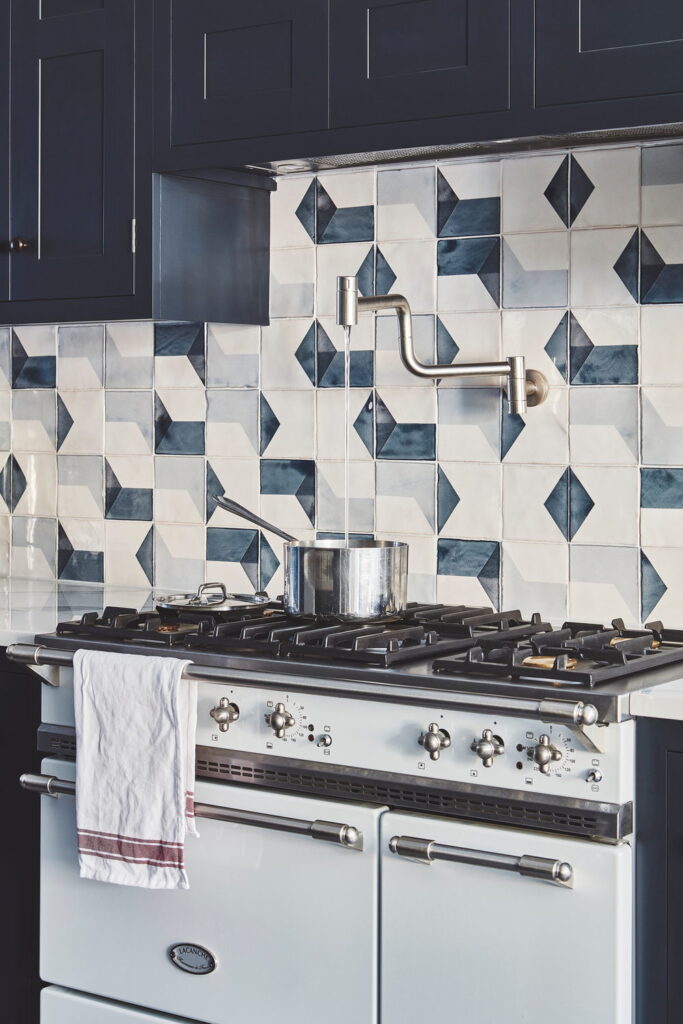Kitchen splashback of Smink Studio handmade ceramic tiles in white, blue and grey diamond pattern with screen-printed colours, set behind a pale blue range cooker.