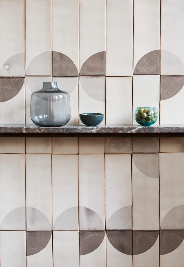 Marble shelf against Smink Studio handmade ceramic tiles in cream with grey half-circle screen-printed colours, styled with a glass vase, bowl and jar.