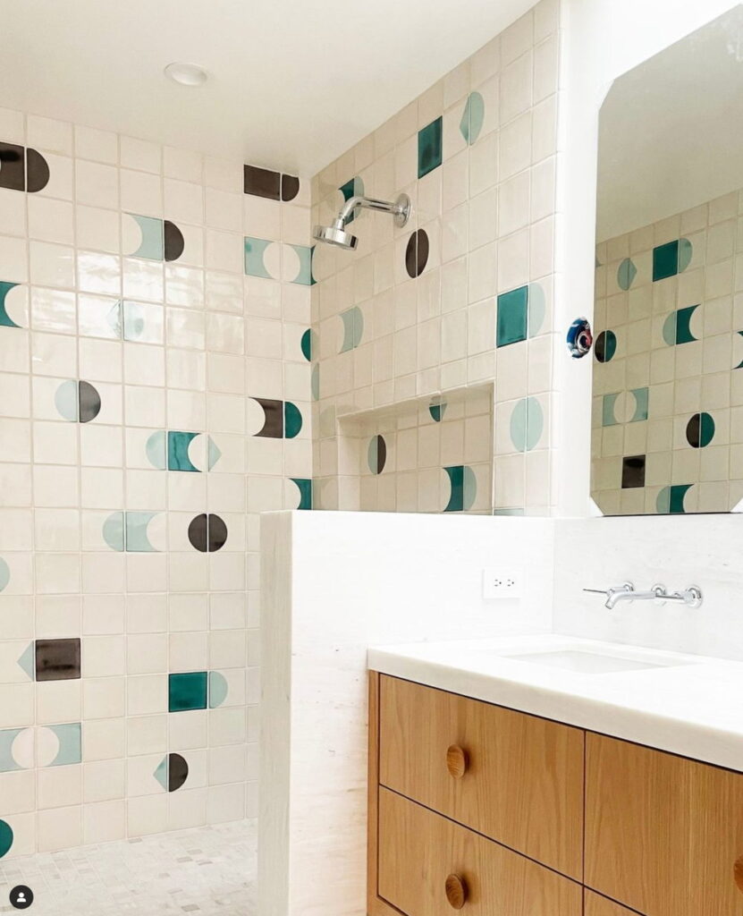 Bathroom of Smink Studio handmade ceramic tiles in cream with teal, aqua and charcoal half-circle screen-printed colours, with a walk-in shower and oak vanity.
