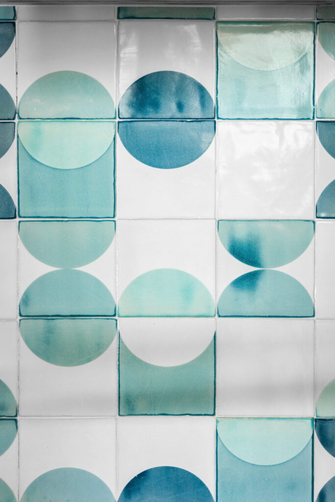 Close-up of Smink Studio handmade ceramic tiles in white, turquoise and teal with a circle pattern in glossy screen-printed colours.