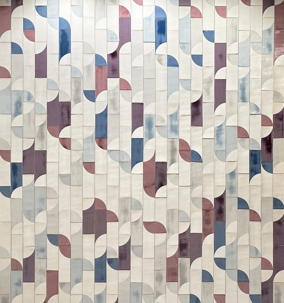 Wall of tall Smink Studio handmade ceramic tiles in cream, blue, plum and grey with half-circle screen-printed colours.