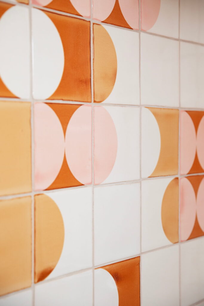 Close-up of Smink Studio handmade ceramic tiles in white, orange, mustard and pink with a half-circle pattern in screen-printed colours.