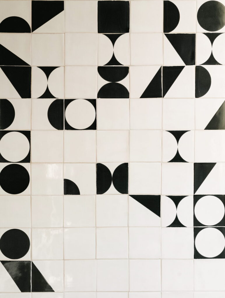 Flat-lay of black and white Smink Studio handmade ceramic tiles with bold half-circle, circle and triangle screen-printed colours.