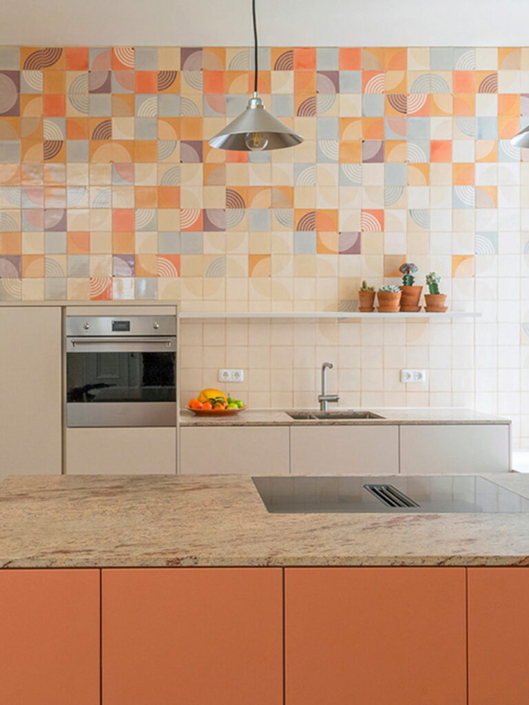 Kitchen backed by Smink Studio handmade ceramic tiles in cream, orange, grey and mauve with circle and concentric-arc screen-printed colours, with terracotta cabinets.